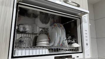 A dishwasher with a transparent door, displaying various dishes and utensils inside.