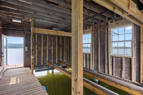 Una cabaña de madera con un muelle que se extiende sobre el agua, con un ventanal grande y vistas al paisaje.