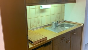 Eine Küche mit Holzausstattung, einer Edelstahlspüle und einer Rückwand mit grünen Fliesen.