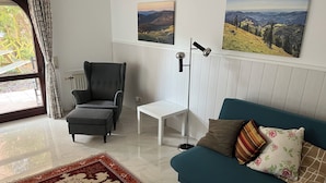 Ein Wohnzimmer mit einem blauen Sofa, einem grauen Sessel, einem weißen Tisch und einem gemusterten Teppich.