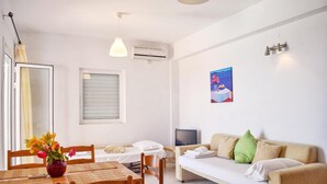 A compact living space with a dining area, a sofa, a TV, and a painting on the wall. - Ostria's House (Kefalonia)