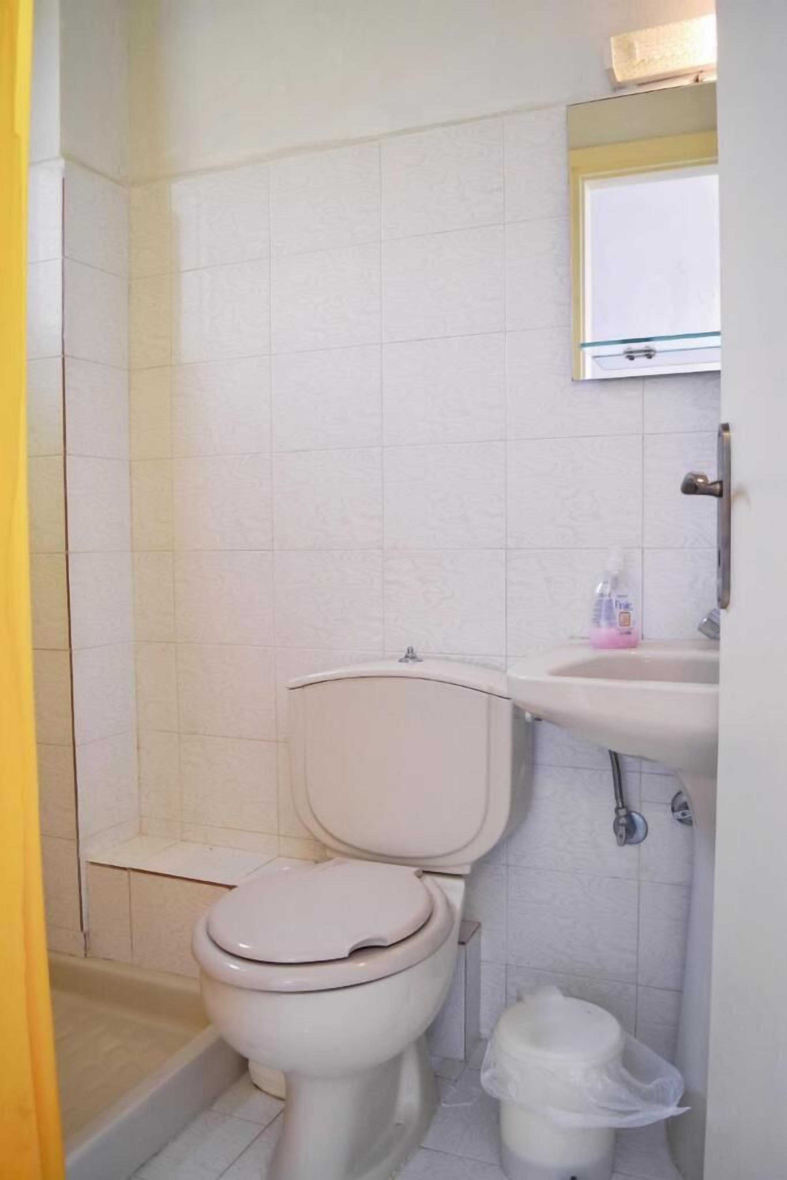 A small bathroom with a toilet, sink, and shower.