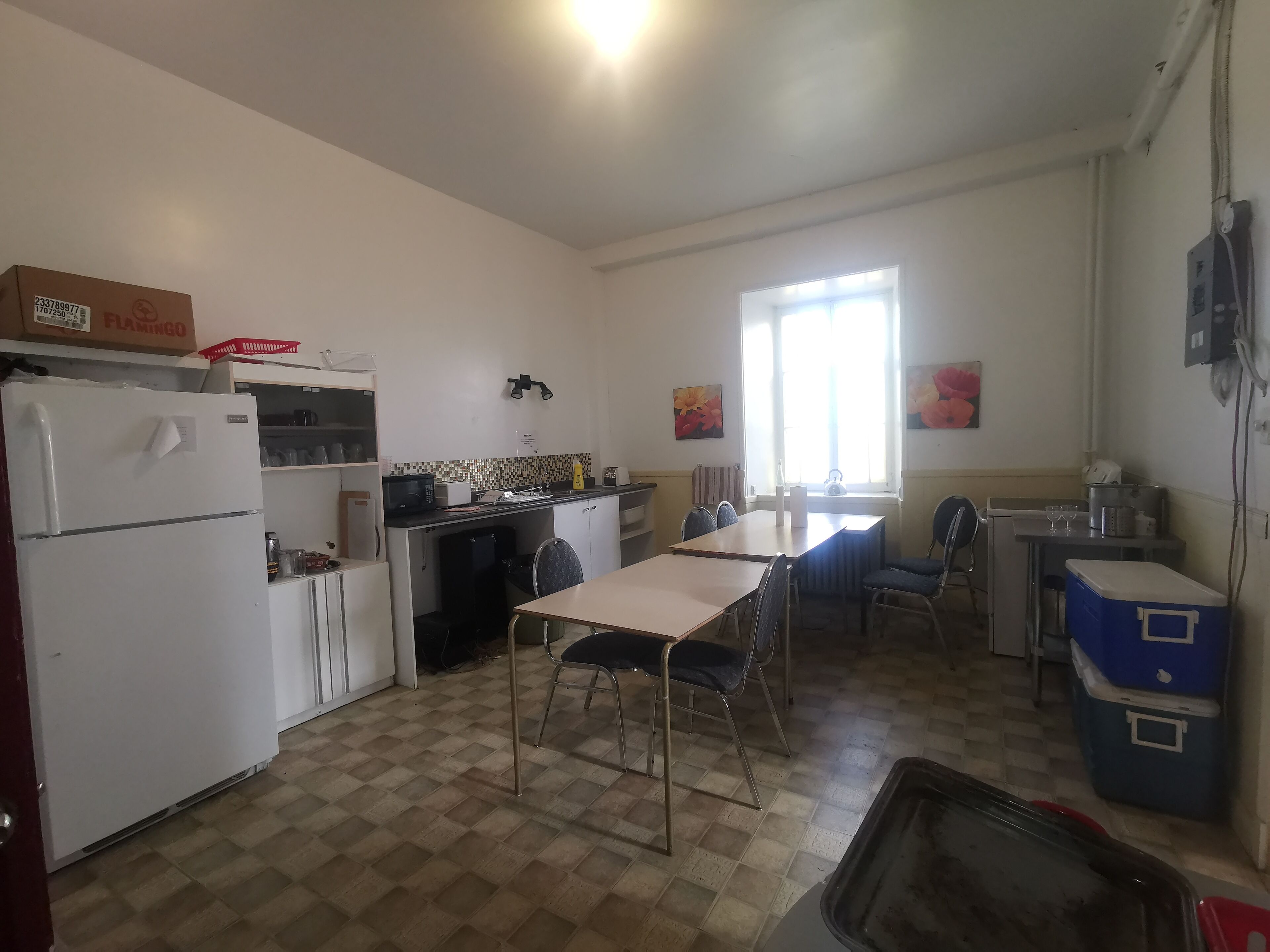 A compact kitchen with a refrigerator, microwave, and small dining table with chairs.