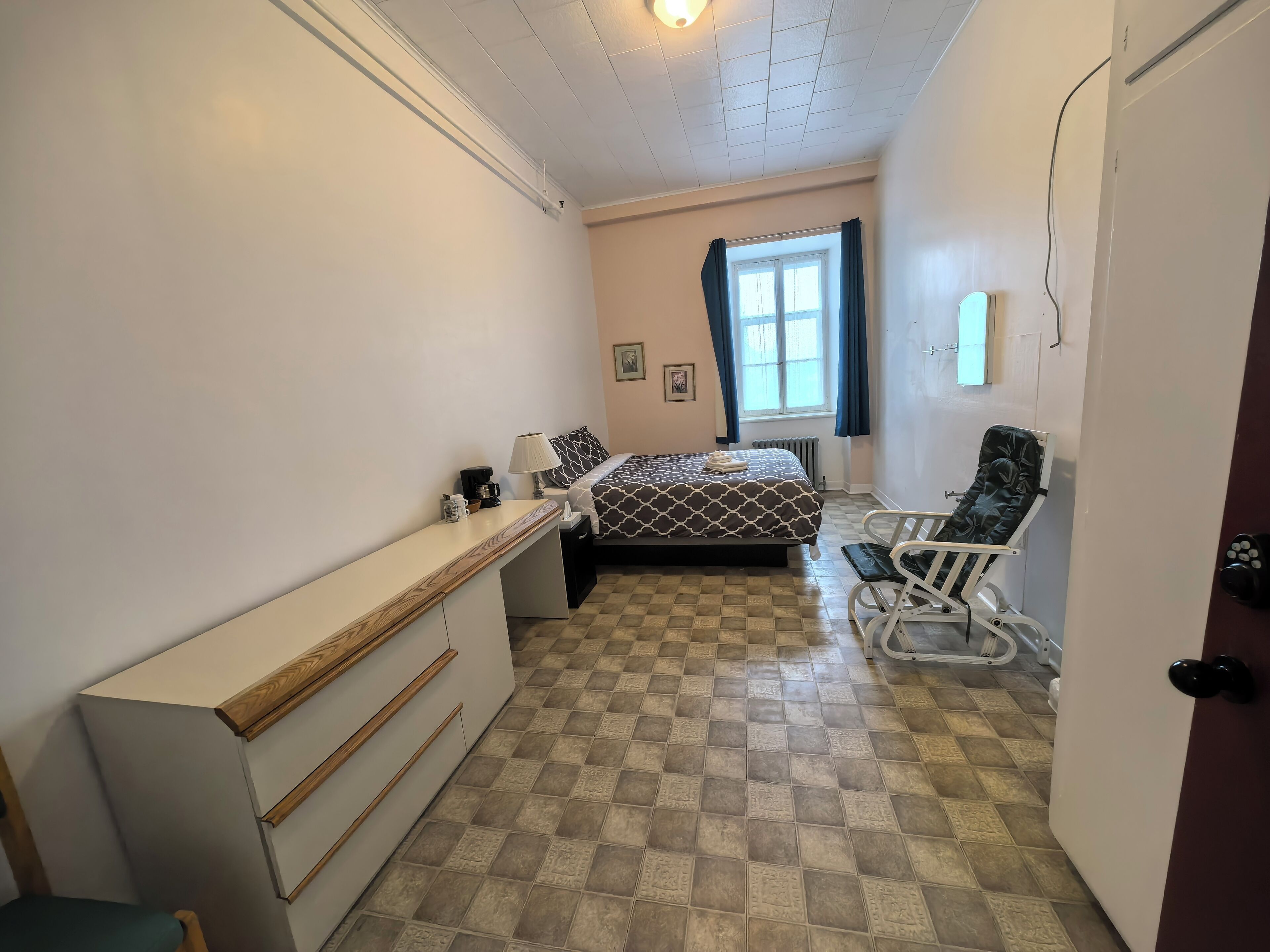 Habitació petita i neta amb llit, escriptori, cadira i radiador.