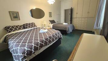 Une chambre d’hôtel avec deux lits, un bureau, une chaise, une armoire et un miroir.