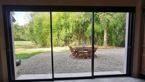 Une pièce dotée d’une grande porte-fenêtre coulissante donnant sur un espace extérieur aménagé avec une table et des chaises.