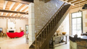 Un vaste espace de vie agrémenté d’un escalier en bois, d’un fauteuil rouge et d’une cheminée.
