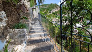 Un escalier en pierre, agrémenté de rampes métalliques, mène à une pente.