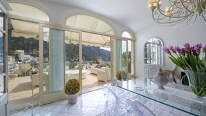Un balcon spacieux offrant une vue dégagée sur les montagnes, une table en verre et un vase rempli de fleurs.