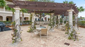 An outdoor patio with a pergola, seating area, and a pool. - This adorable studio in The Villages of South Walton is tastefully decorated! (Seacrest)