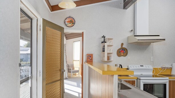 Une cuisine compacte avec un comptoir en bois, des appareils électroménagers blancs et une vue sur l’extérieur.