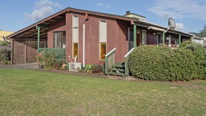 Une maison à deux étages, dotée d’une antenne parabolique, d’un porche verdoyant et d’une pelouse bien entretenue.