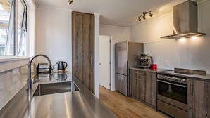 Eine moderne Küche mit Edelstahlgeräten, einem Holflanschrank und einem Fenster, das für natürliches Licht sorgt.