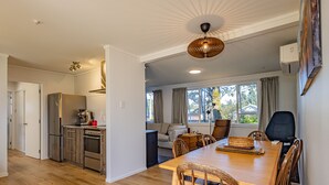 Eine moderne Küche mit Kühlschrank, Herd und Kaffeemaschine. Ein Essbereich mit Holztisch und Stühlen ist ebenfalls vorhanden.