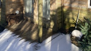 Eine Holzhütte mit einer Tür, einem farbigen Glasfenster und einem kleinen angebauten Schuppen.