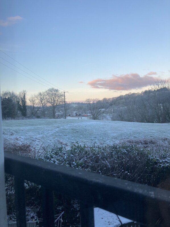 A frosty landscape with a clear sky, a bench, and leafless trees.