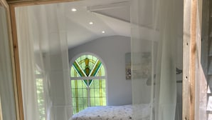 Ein Schlafzimmer mit einem Bett, einem Fenster mit Buntglas und Holzboden.