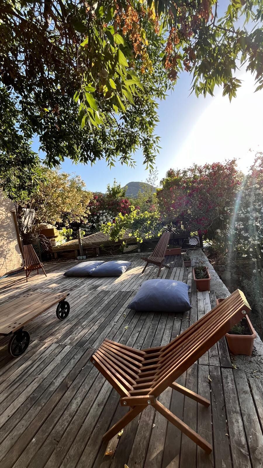 A wooden deck with lounge chairs, cushions, and a small table.