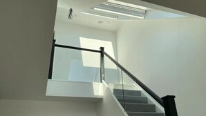 A modern staircase with glass railings and a skylight above.
