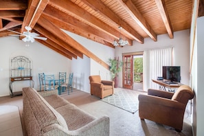 Relax in this spacious living area with a high ceiling, featuring a large sofa, armchairs, and a dining table.