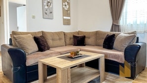 Ein modernes Wohnzimmer mit einem beigefarbenen Ecksofa, einem Holztisch und zwei floralen Kunstwerken an der Wand.