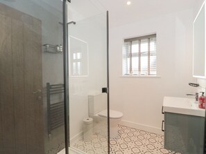 A modern bathroom with a glass shower enclosure, a toilet, and a sink with a mirror. - Little Haven (Blandford Forum)