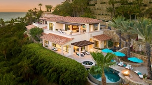 Una casa de varios pisos con piscina, mobiliario exterior y vistas al océano.