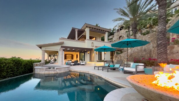 Una casa lujosa con piscina, zona de estar exterior y chimenea al aire libre.