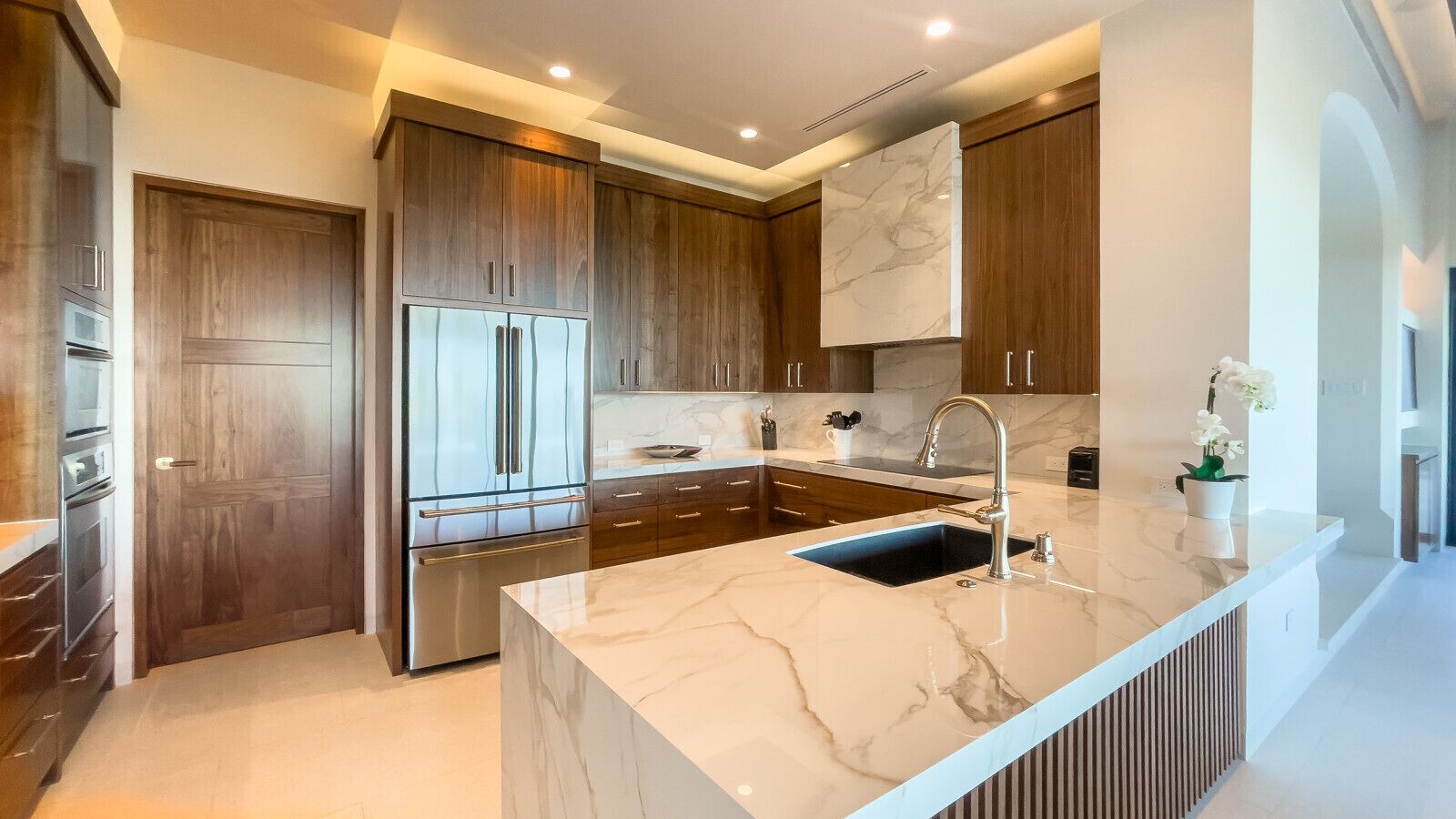 A modern kitchen with dark wood cabinets, stainless steel appliances, and a marble countertop.