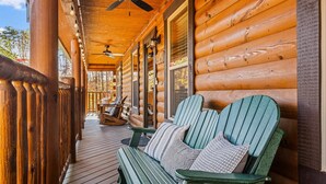 A wooden cabin with a porch, green Adirondack chairs, and a ceiling fan. - Near PF & Dollywood! 4 BD Retreat-Theater-Arcades-Hot Tub-Fire Pit-Pool Table (Sevierville)