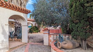 Un patio con tejado de baldosas, pared de piedra y un gran árbol.