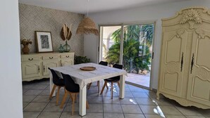 Un comedor con una mesa, sillas, una lámpara decorativa colgante, un armario y vistas al exterior.