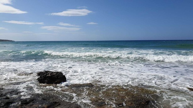 Une côte rocheuse où les vagues se brisent sur la plage.
