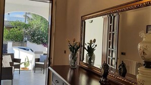 Une pièce dotée d’un grand miroir, d’une commode en bois foncé et d’un luminaire suspendu.