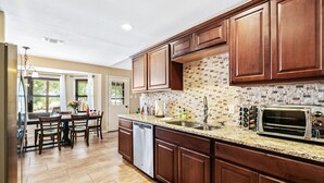 A modern kitchen with wooden cabinets, a granite countertop, and a built-in dishwasher.