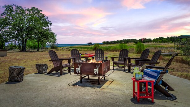 An outdoor seating area with Adirondack chairs and a fire pit, surrounded by a scenic landscape.