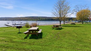 En picknickplats vid sjön med träbänkar och en brygga.