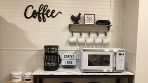 Un área de cocina con estación de café, que incluye una cafetera, un microondas y un cartel que dice 
