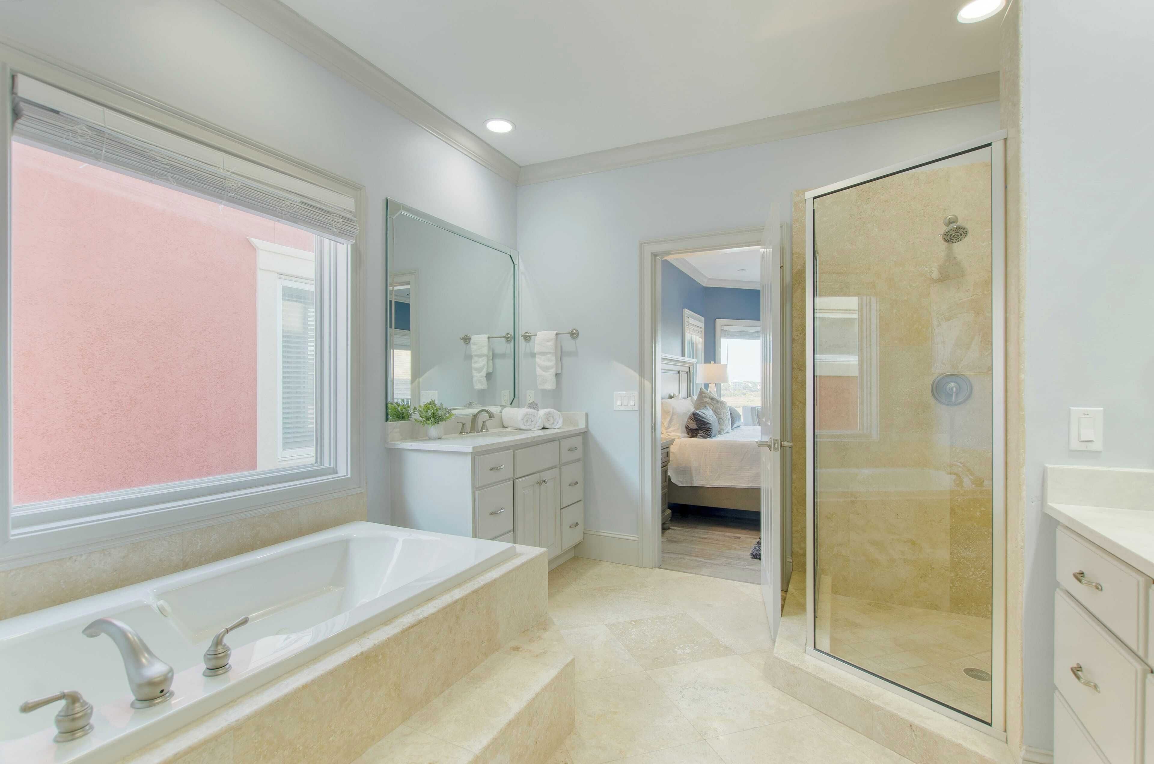 A modern bathroom with a large bathtub, a glass-enclosed shower, and a walk-in closet.