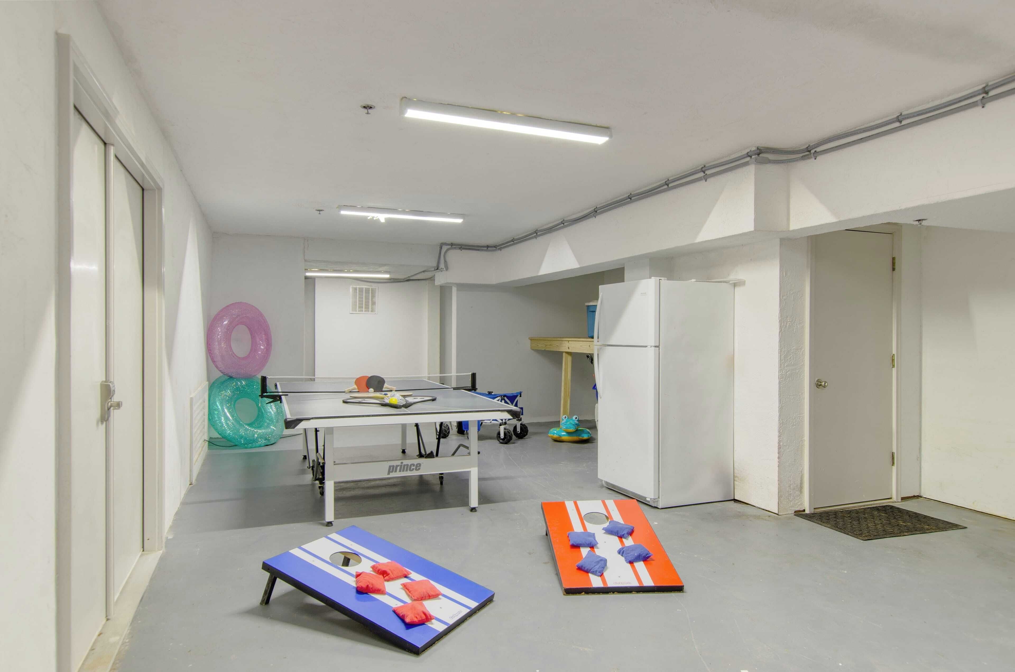 A room with a ping pong table, two small exercise mats, and a refrigerator.