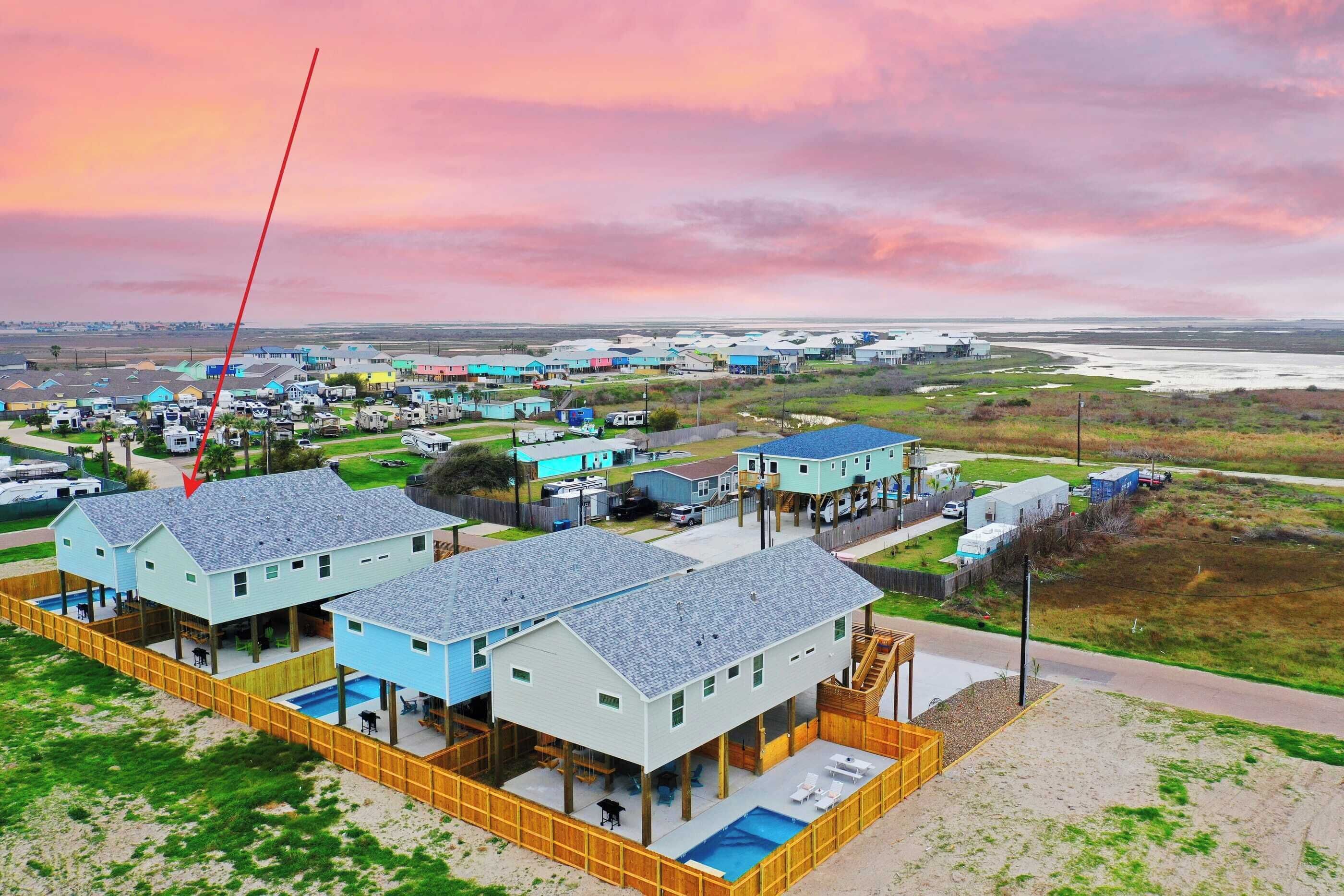 A coastal residential area with multiple houses, a swimming pool, and a view of the ocean.