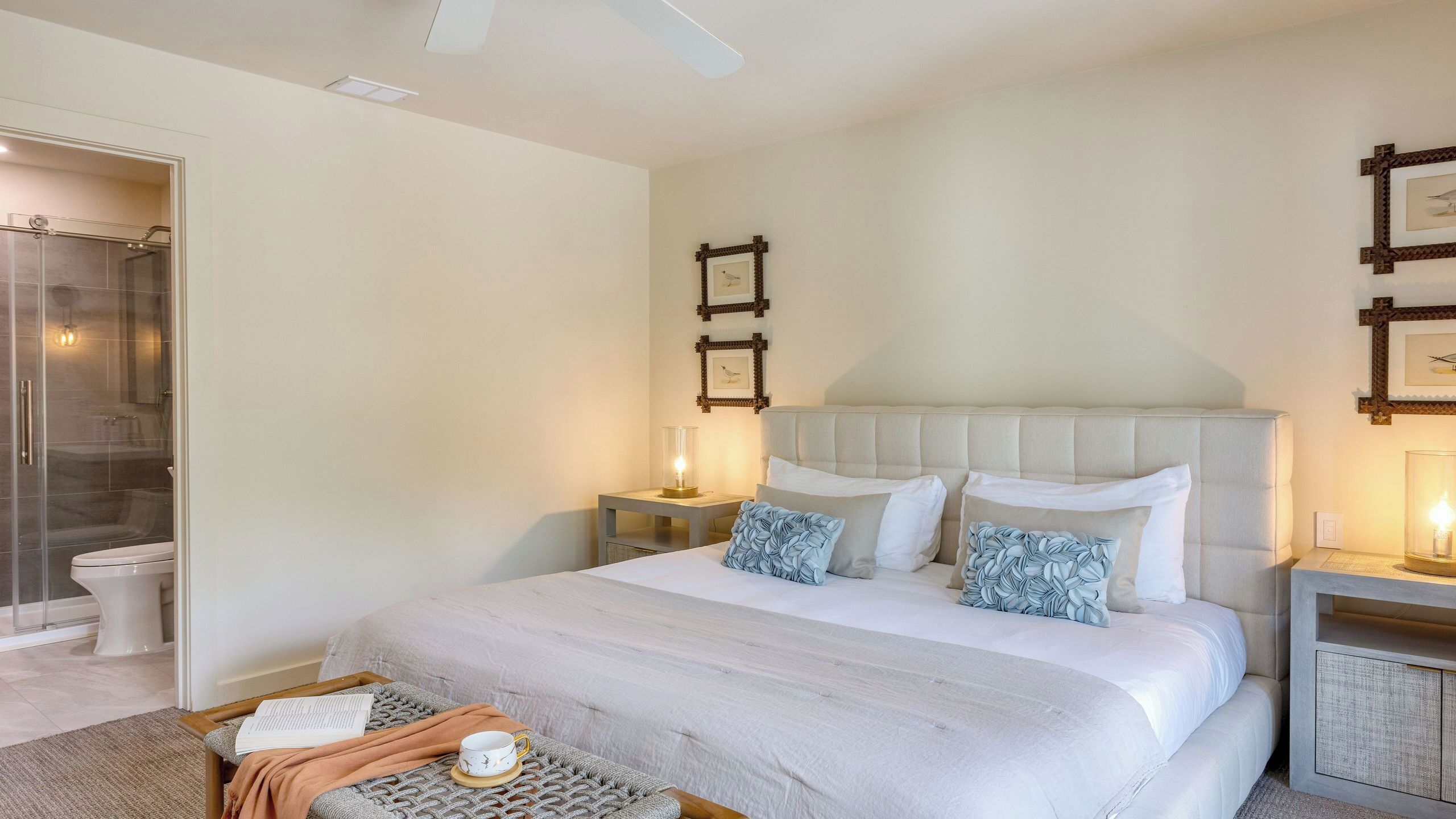 A bedroom with a bed, bedside tables, a nightstand, a window, and a shower area.