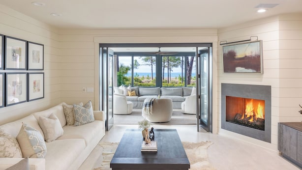 Un salon moderne avec un canapé, une table basse, une cheminée et une vue sur l’extérieur.