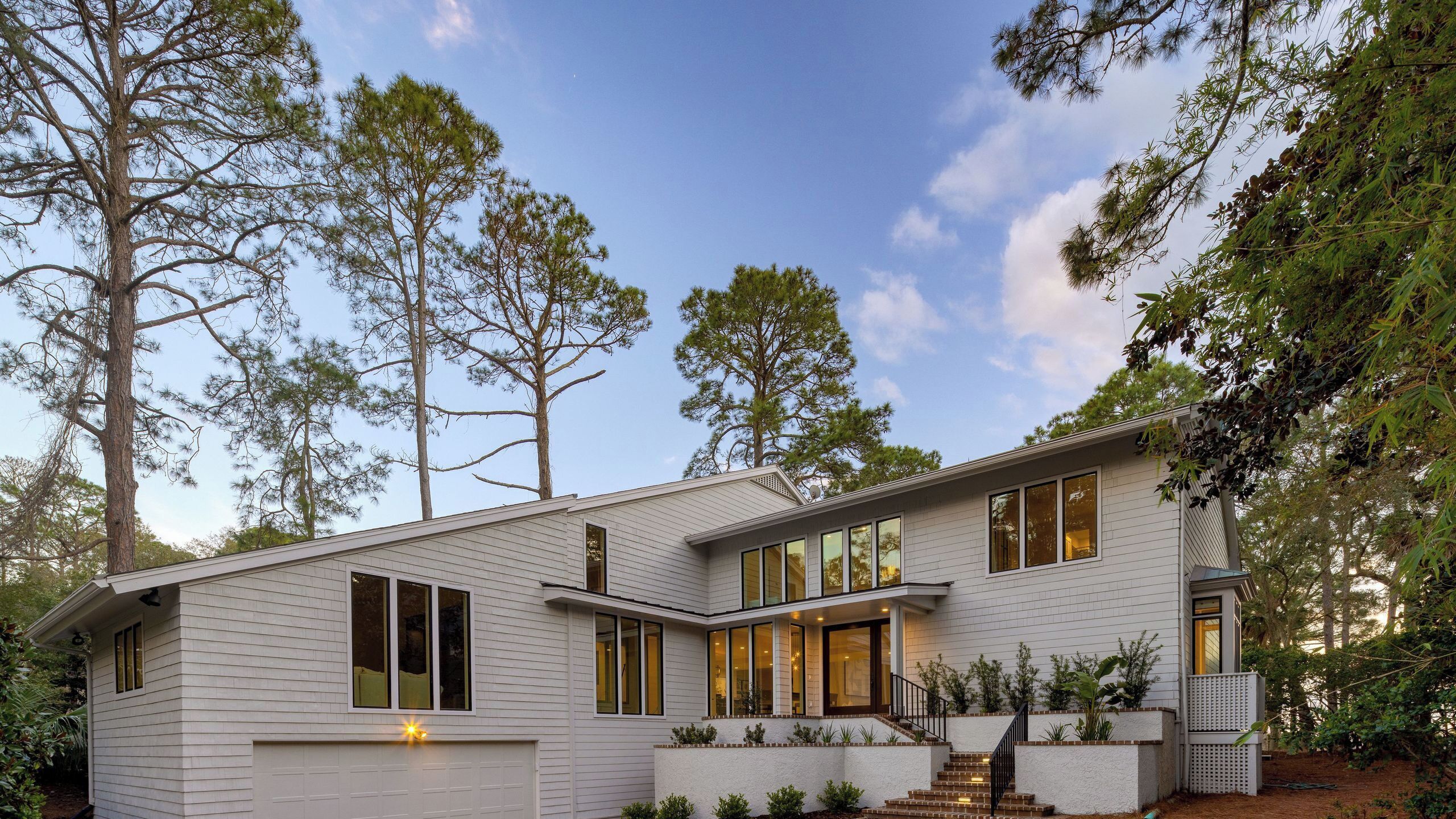 A modern two-story house with a garage, large windows, and a well-maintained garden.