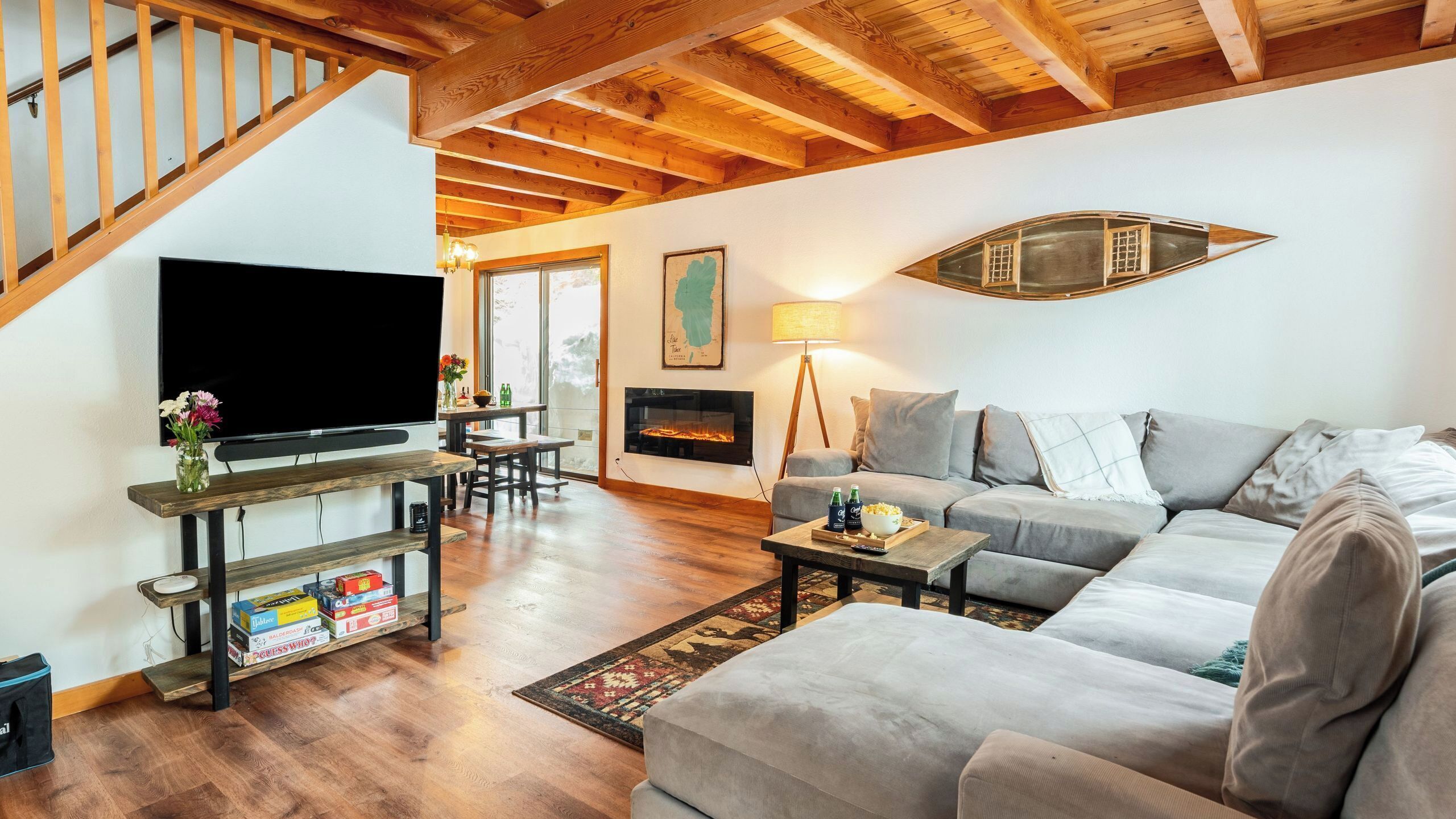 Una sala de estar con televisor, sofá, chimenea y vigas de madera.