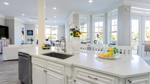 A spacious kitchen with a large island, white cabinetry, and a view of the outdoors through large windows. - Steps to Beach Pool, Hot Tub, Fire Pit 7br, Sleeps 18 Cobalt Coast (Hilton Head Island)
