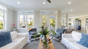 A spacious living room with white sofas, a coffee table, and a glass-top table with plants. - Steps to Beach Pool, Hot Tub, Fire Pit 7br, Sleeps 18 Cobalt Coast (Hilton Head Island)