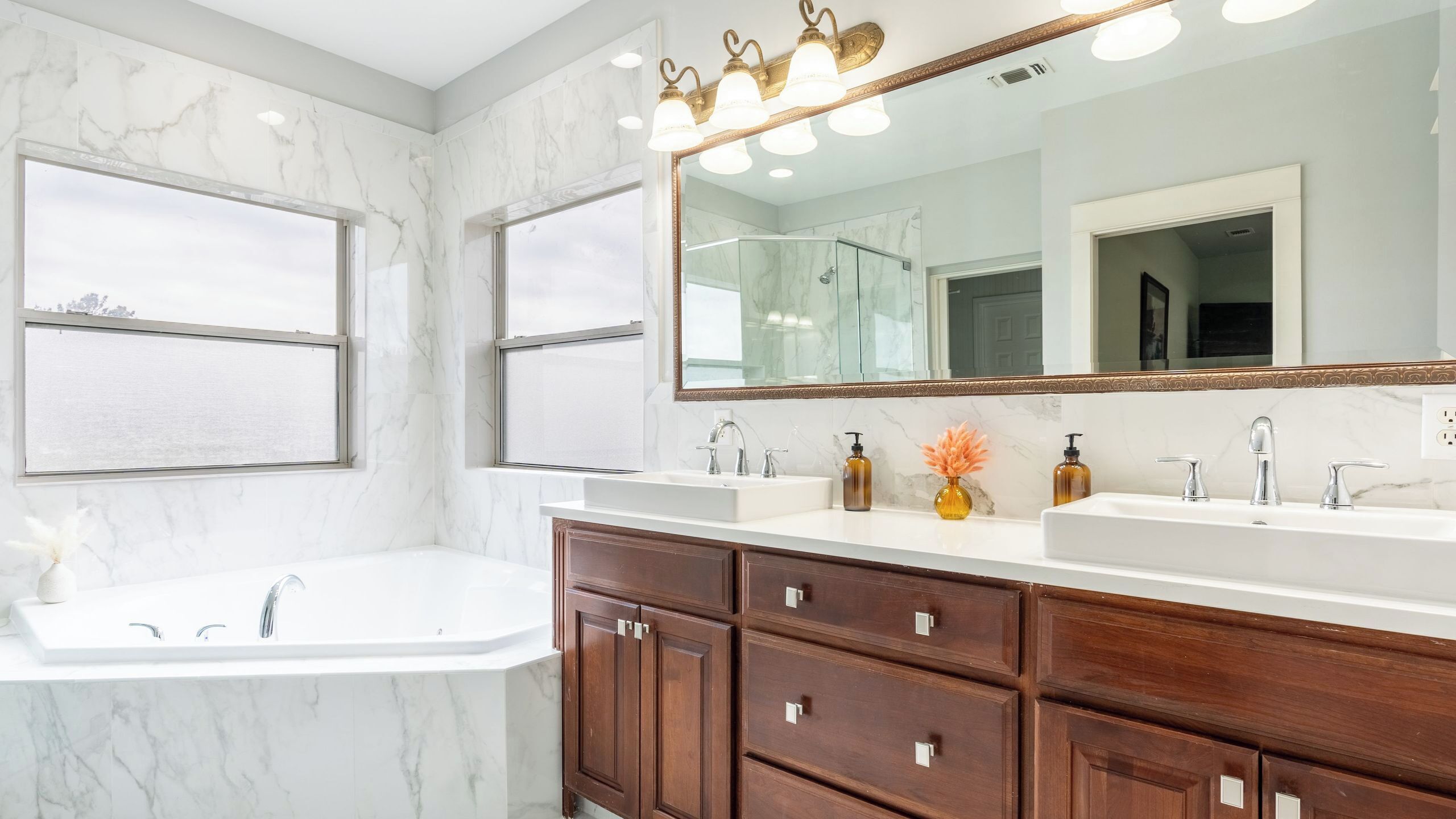 A bathroom with two sinks, a large mirror, and a shower.