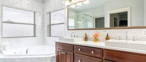 A bathroom with two sinks, a large mirror, and a shower.