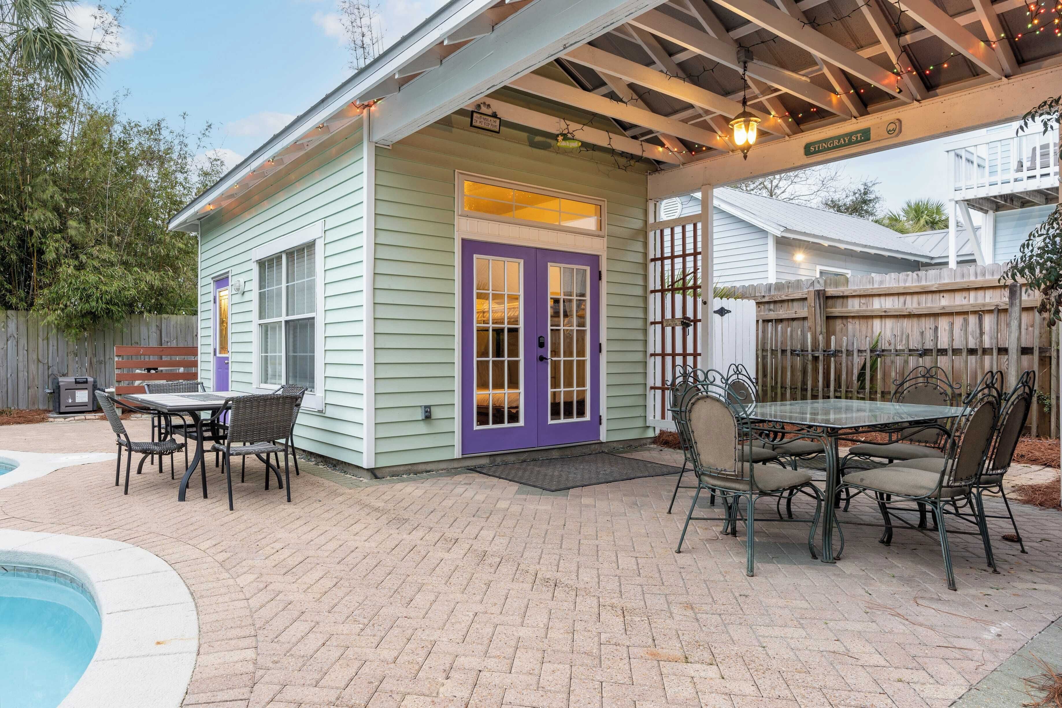 A house with a covered patio, a pool, and a dining area with outdoor furniture.